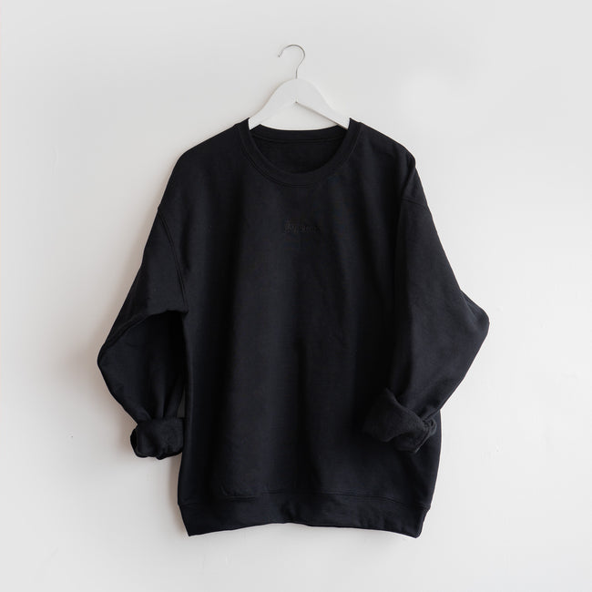 crewneck noir flambette accroché sur le mur